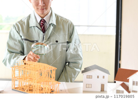 虫眼鏡で建築模型を覗く作業服姿の男性 虫眼鏡で建築模型を覗く作業服姿の男性 117019805