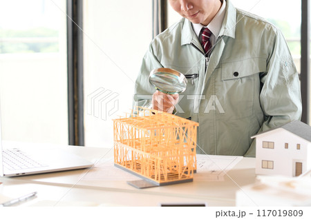 虫眼鏡で建築模型を覗く作業服姿の男性 117019809