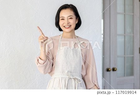 キッチンで指差しをする笑顔のミドル女性 キッチンで指差しをする笑顔のミドル女性 117019914