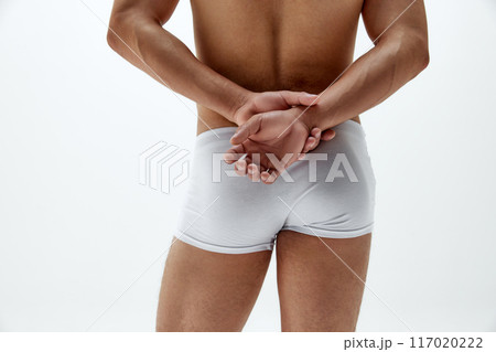 Rear view photo of fit man in boxers posing holds hands behind his back, highlighting his toned physique against white studio background Rear view photo of fit man in boxers posing holds hands behind his back, highlighting his toned physique against white studio background 117020222