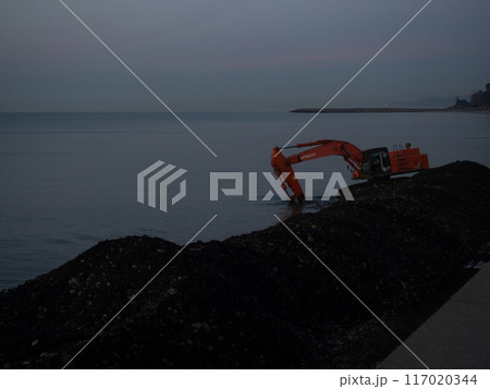 Excavator work at night. Overtime work. The work of construction equipment on the seashore. Batumi. Fortified shores. at sunset. 117020344
