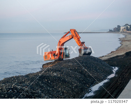 Excavator work at night. Overtime work. The work of construction equipment on the seashore. Batumi. Fortified shores. at sunset. 117020347