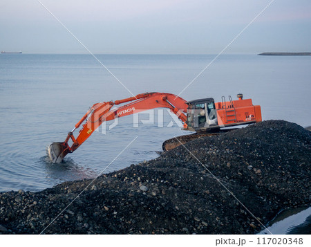 Excavator work at night. Overtime work. The work of construction equipment on the seashore. Batumi. Fortified shores. at sunset. Hitachi Excavator work at night. Overtime work. The work of construction equipment on the seashore. Batumi. Fortified shores. at sunset. Hitachi 117020348
