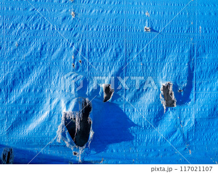 Blue canvas with holes. Leaky fabric. Forgotten. Abandoned. 117021107