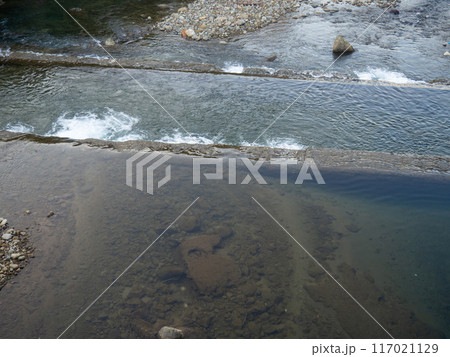 A shallow fast river. Stream with shallows. Concrete rapids on the river A shallow fast river. Stream with shallows. Concrete rapids on the river 117021129