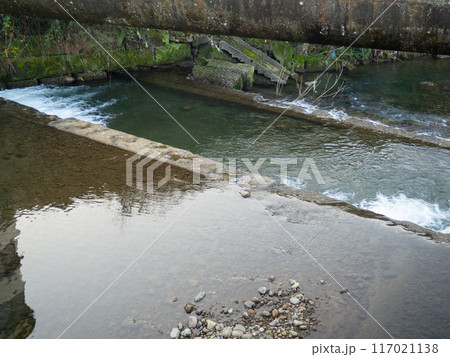 Heating main over the stream. Industry and nature.   Concrete rapids on the river 117021138