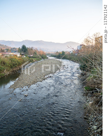 A shallow fast river. Stream with shallows. Fast river in the city. Concrete rapids on the river. River in Georgia. A shallow fast river. Stream with shallows. Fast river in the city. Concrete rapids on the river. River in Georgia. 117021142