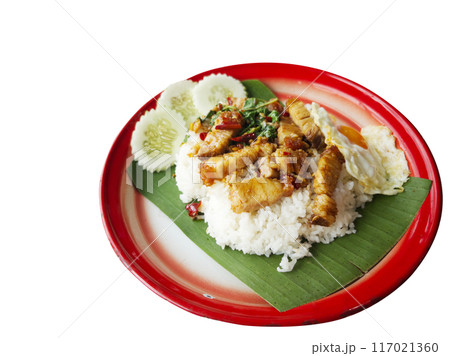 Isolated Thai food on white background. Image of stir-fried crispy pork with holy basil over jasmine rice and fried egg with sliced cucumbers. Food on banana leaf in Thai style vintage tray. 117021360