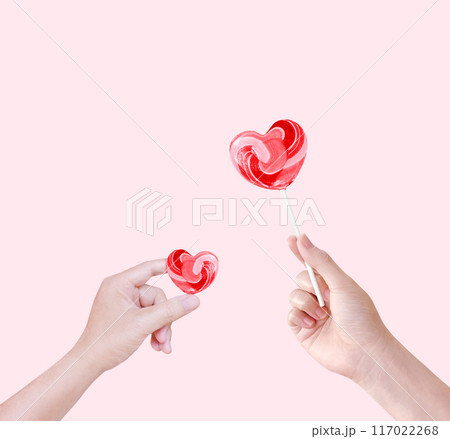 Heart shaped lollipop candy in hand isolated on pink background. 117022268