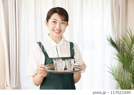 笑顔でお冷を運ぶカフェの女性スタッフ 117022890