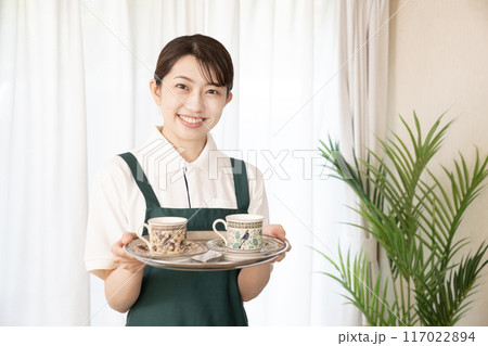 笑顔でお冷を運ぶカフェの女性スタッフ 117022894