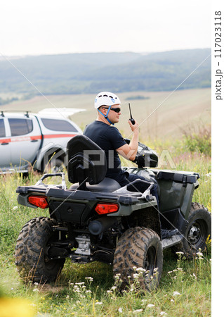 The rescuer, a beautiful athletic physique, rides an ATV in the middle of the field The rescuer, a beautiful athletic physique, rides an ATV in the middle of the field 117023118