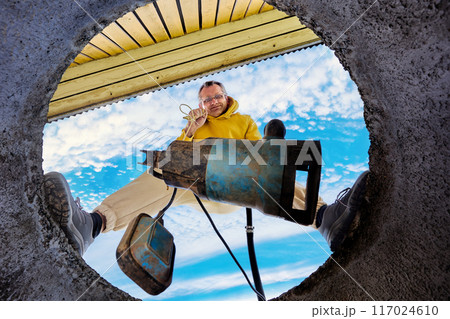 Septic tank pumping, bottom view of man installing submersible sewage pump into concrete well ring. 117024610