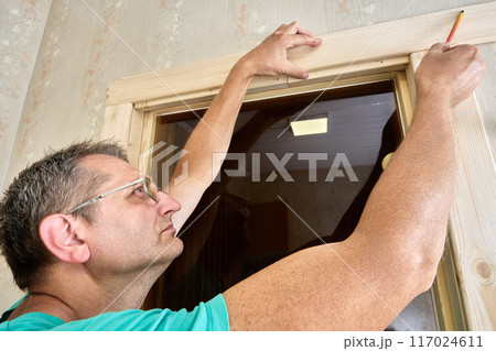 Creating marking door frame using pencil and piece of trim. 117024611