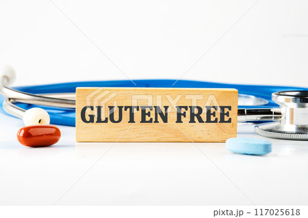 top view Phrase Gluten free written on a wooden block with a stethoscope lying next to it, pills, vitamins on a white background 117025618