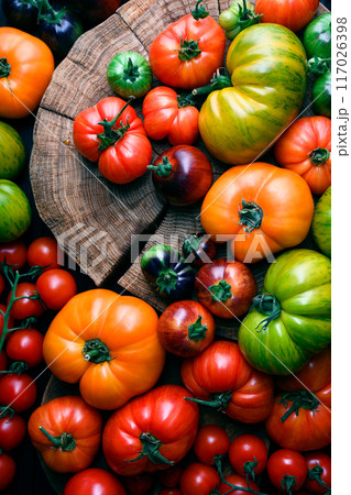 Different sizes and varieties ripe tomatoes on wooden cutting board Different sizes and varieties ripe tomatoes on wooden cutting board 117026398