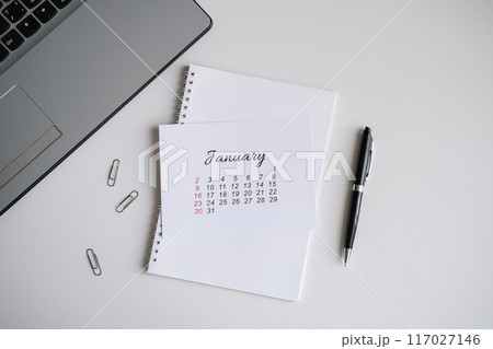January calendar, notepad and laptop on the office table 117027146