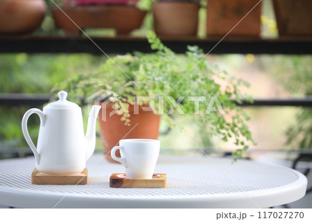 white ceramic teapot and white ceramic cup with plant pot on metal table at balcony outdoor 117027270