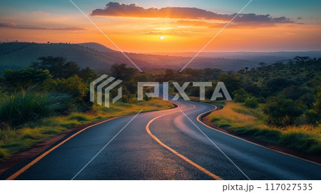 Serene winding road at sunset with scenic hills and lush greenery, perfect for travel and adventure concepts. 117027535