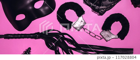 set of BDSM sex toys with handcuffs, whip flogger for submission and domination on a pink background set of BDSM sex toys with handcuffs, whip flogger for submission and domination on a pink background 117028804