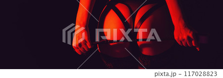woman dominant mistress girl with a sexy ass in panties holding a leather whip flogger in female hands. BDSM sex with submission and domination. Wide banner with a black background 117028823