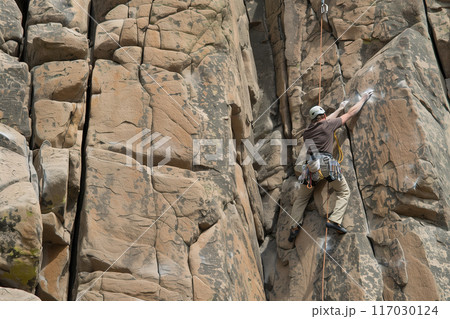 Rock climbing on towering granite cliffs, professional rock climber climbs cliff, extreme sport Rock climbing on towering granite cliffs, professional rock climber climbs cliff, extreme sport 117030124