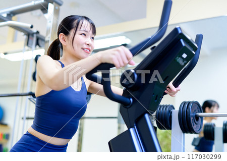 ジムで体を鍛える女性　エアロバイク　フィットネスバイク　筋トレ女子　ダイエット 117030299