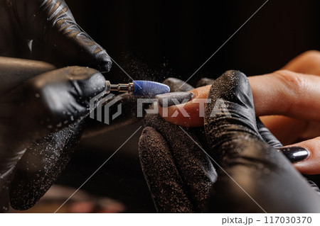 Manicurist doing hardware manicure to female client using special tools Manicurist doing hardware manicure to female client using special tools 117030370