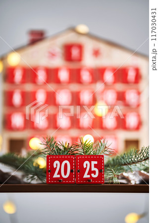 Christmas Advent calendar in the shape of a house with boxes making up the number 2025. 117030431