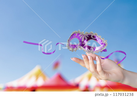Hand shows mask against background of festive sky. Hand shows mask against background of festive sky. 117031238