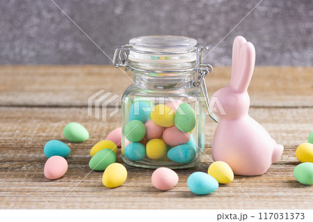 Easter composition with pink bunny and a jar with colorful candies. Easter composition with pink bunny and a jar with colorful candies. 117031373