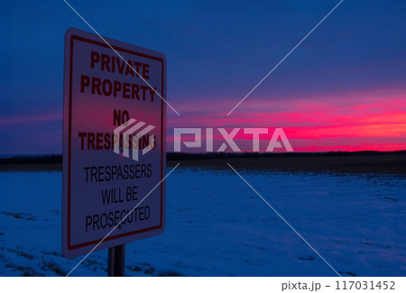 Sign "No trespassing" in the agricultural field in sunset light in winter. 117031452