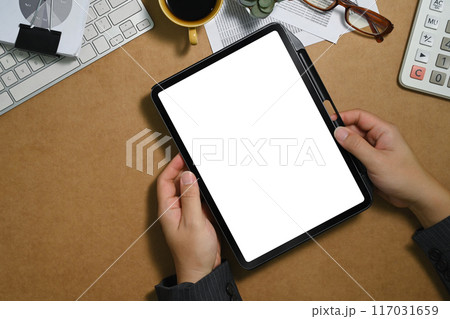 Above shot of young businessman holding digital tablet over working desk with calculator and documents Above shot of young businessman holding digital tablet over working desk with calculator and documents 117031659