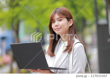 新緑の街でノートPCを立ち上げるビジネスウーマン_1 新緑の街でノートPCを立ち上げるビジネスウーマン_1 117033307
