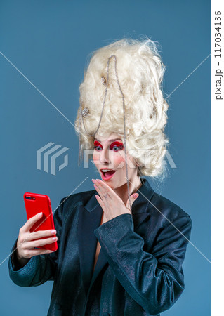 Amazed woman in makeup and royal wig using 117034136