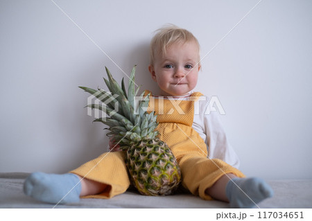 A cute child hold pineapple at home A cute child hold pineapple at home 117034651