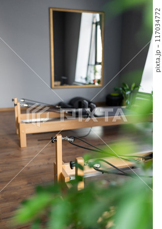 Pilates equipment. Reformer bed. Reformer pilates studio machine for fitness workouts in gym. Fit, healthy and strong authentical body. Fitness concept 117034772