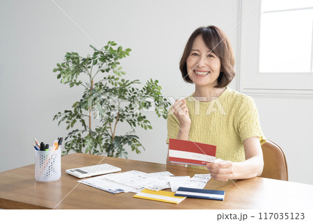 預金通帳を持って笑う女性 預金通帳を持って笑う女性 117035123