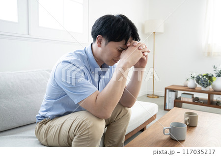 ソファーに座って悩む男性 117035217