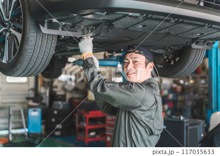 リフトに上がる車両の下でアンダーカバーを外し整備・点検・作業をする自動車整備士の男性 リフトに上がる車両の下でアンダーカバーを外し整備・点検・作業をする自動車整備士の男性 117035633