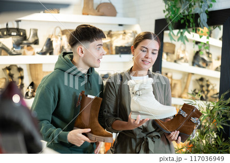 Young couple shopping for comfortable fall footwear in shoe store Young couple shopping for comfortable fall footwear in shoe store 117036949