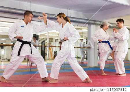Young woman in kimono sparring with male partner during martial arts training 117037312
