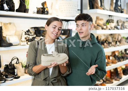 Young man with female friend view moccasins in footwear store 117037316