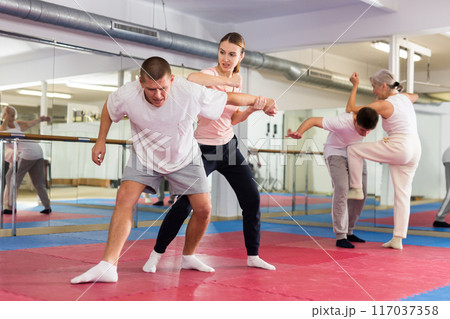 Girl performing elbow strike and wristlock to man in self defence training 117037358