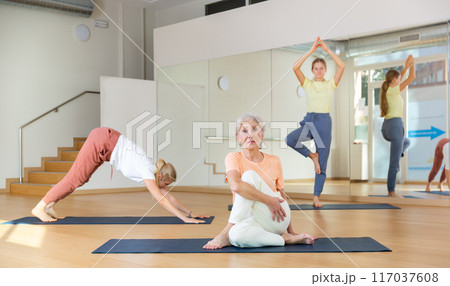 Portrait of woman practicing yoga in group, making twisting asana 117037608
