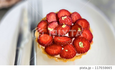Delicious strawberry tart or tartlet with cut out strawberries and whipped cream decorated with edible gold flakes, good for multimedia recipe content 117038665