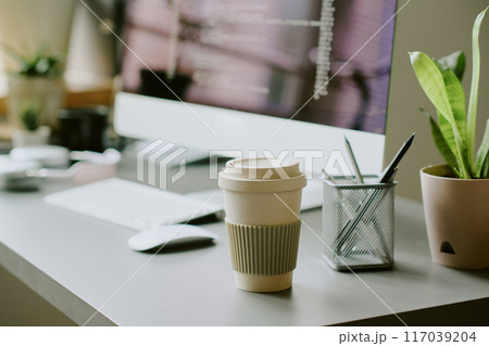 No people shot of reusable coffee cup on table at workplace in modern IT company office No people shot of reusable coffee cup on table at workplace in modern IT company office 117039204