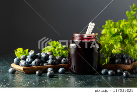 Blueberry jam and fresh berries with leaves. Blueberry jam and fresh berries with leaves. 117039829