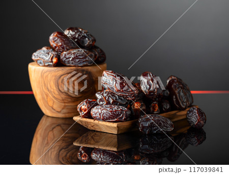 Dates in wooden dish on a black background. Dates in wooden dish on a black background. 117039841