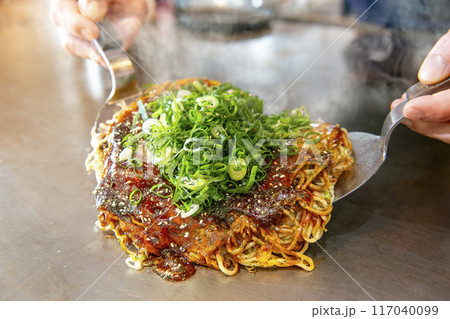 鉄板で焼く美味しそうなお好み焼き 117040099